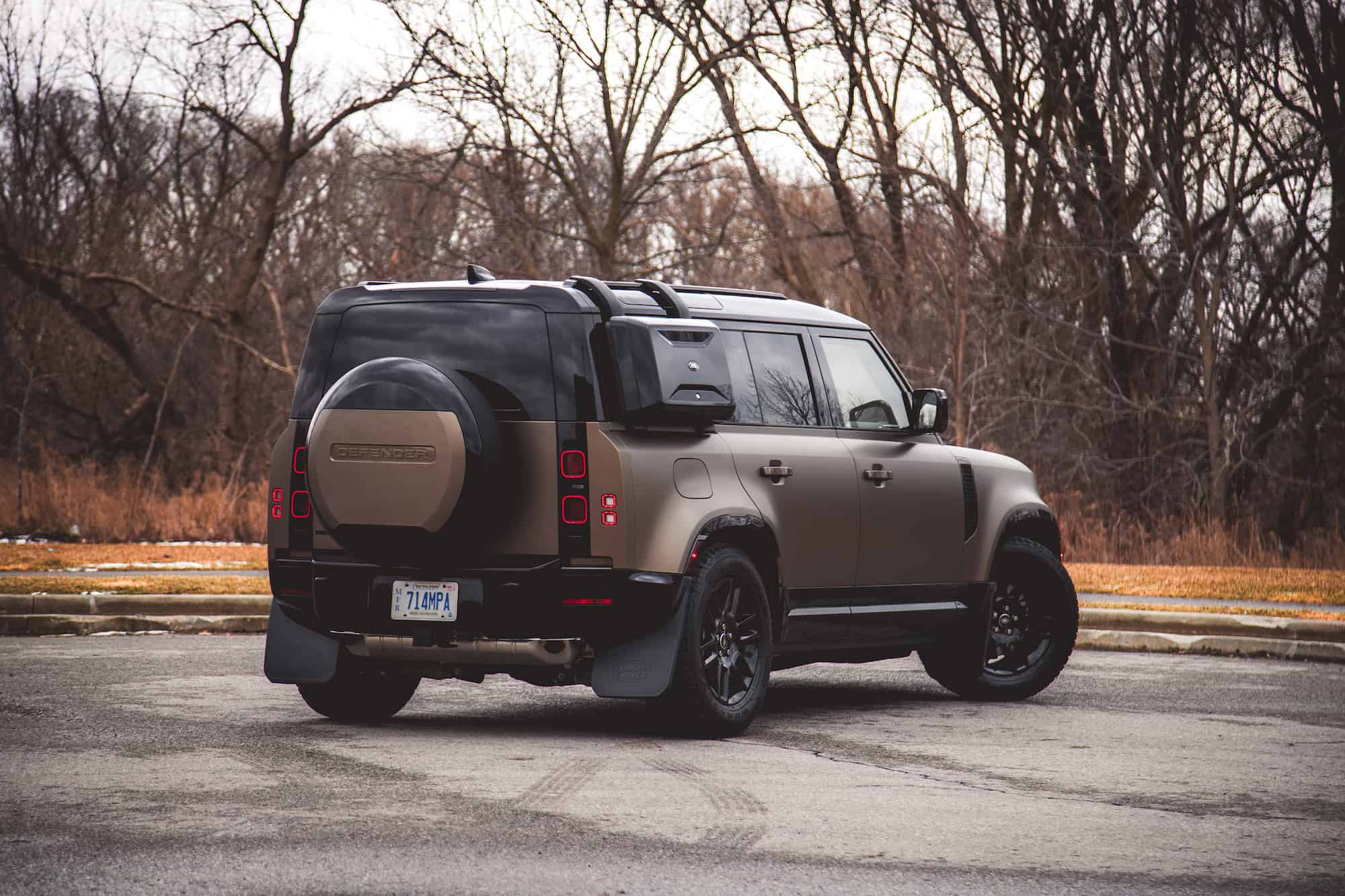 Luxury Land Rover Defender SUV parked outdoors in natural setting.