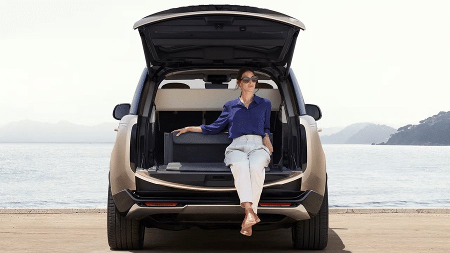 2026 Land Rover Range Rover rear view with open liftgate, woman seated by the sea